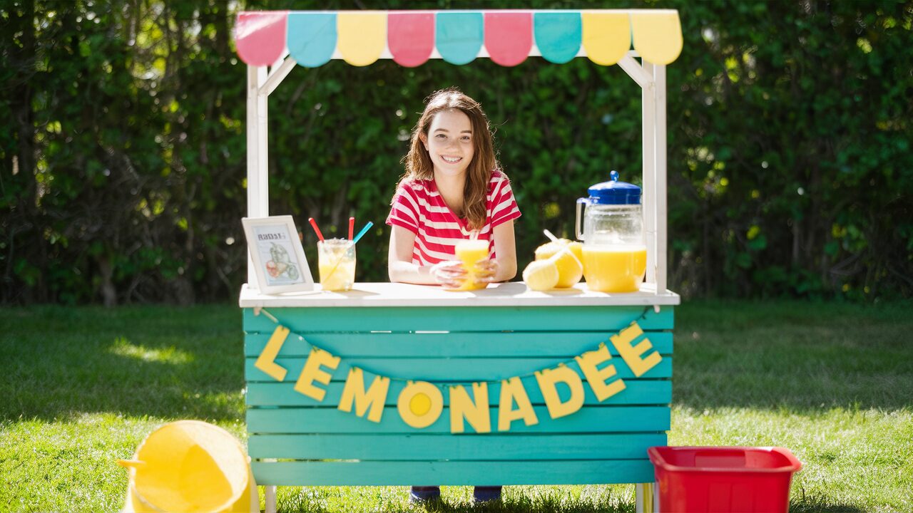 12 years old girl standing at lemonade stand and making extra side money